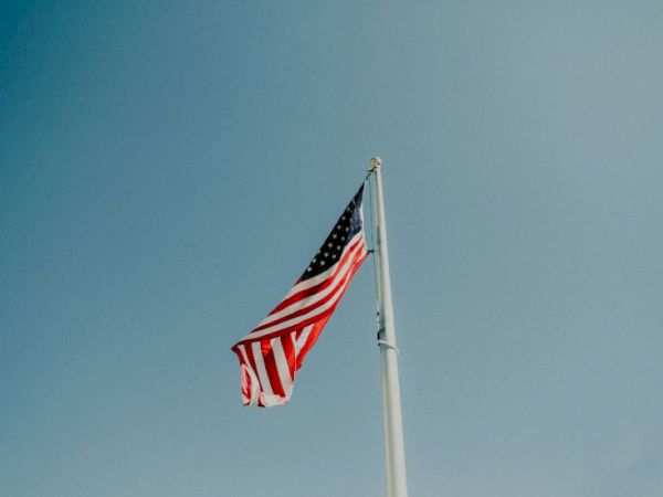 An American flag waving on a tall flagpole against a clear blue sky.
