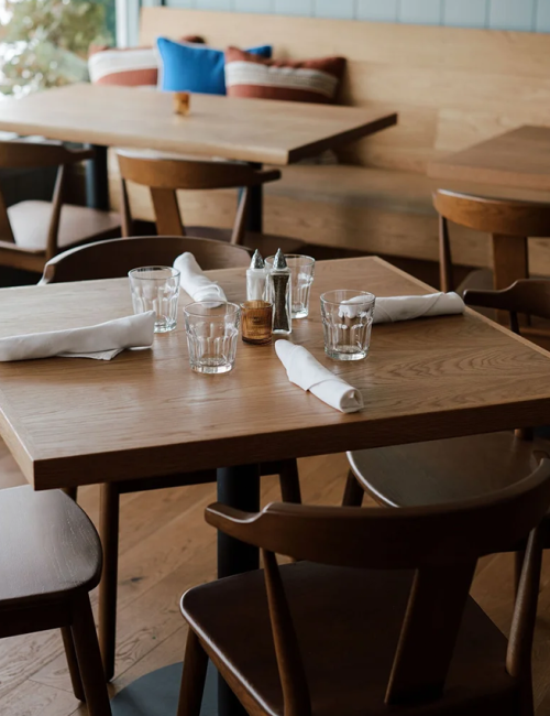 A set dining table with glassware, folded napkins, and lit candleholders in a cozy restaurant.