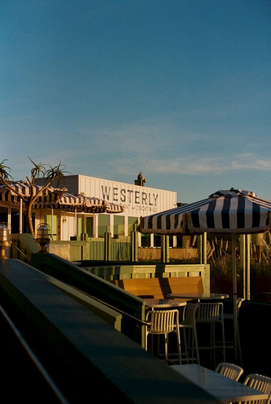 A sunny outdoor patio at the Westerly resort, with striped awning, lounge chairs, and a warm poolside view.